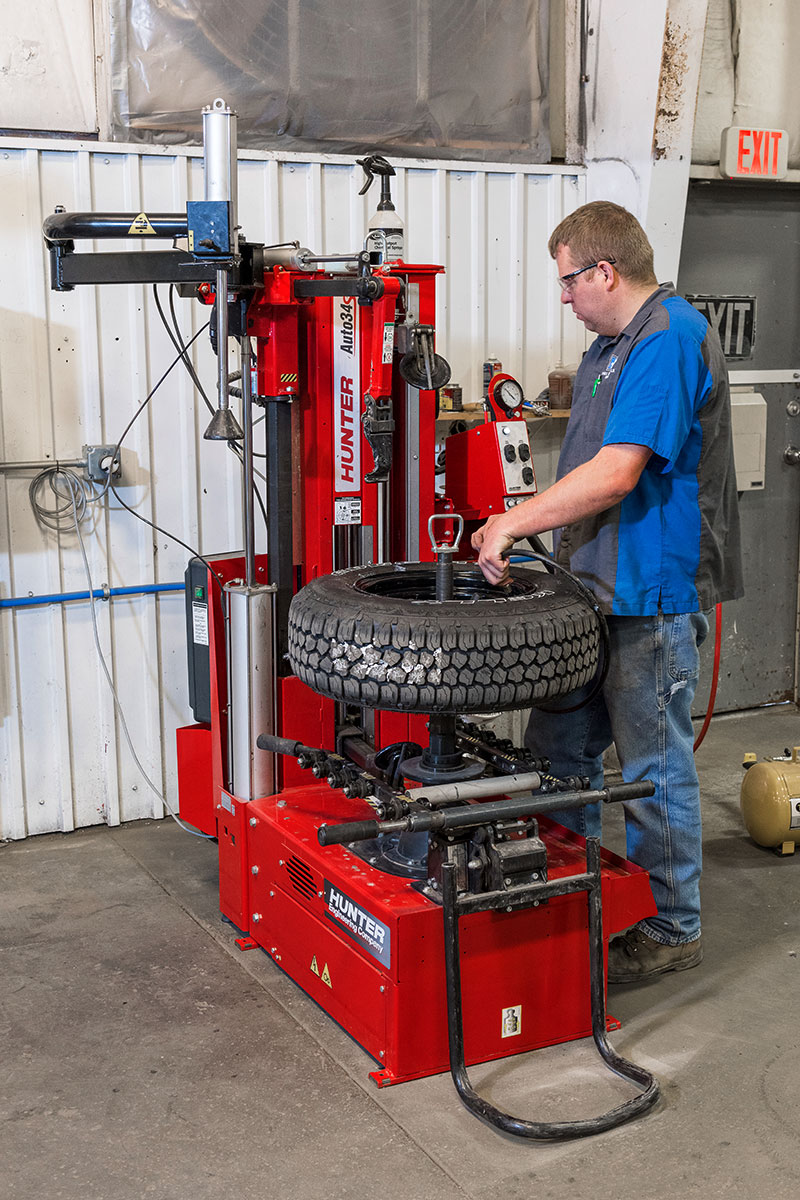 tc-tca-realshop-fullthrottle1.jpg technician using blast inflator on hunter auto34s tire changer